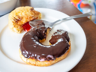 Bitten chocolate and strawberry jam donuts on white dish