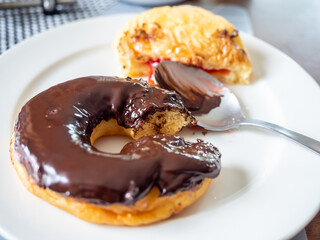 Bitten chocolate and strawberry jam donuts on white dish