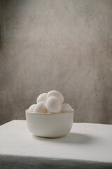 White eggs in the basket . White cloth and old wall background. Still Life composition.