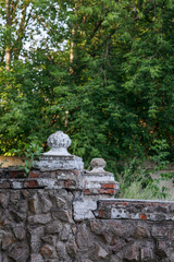 Part of an old building from the early 20th century in an abandoned park. Brick fence with plaster and concrete decorations.