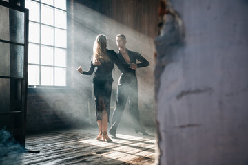 Obraz na płótnie Canvas Couple of two professional ballroom dancers is dancing on loft studio. Beautiful art performance with heavy smoke. Sport life concept. Passion and emotional dance.