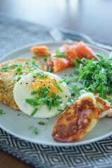 Cozy homemade breakfast: potato pancakes with scrambled eggs, red fish, cheese and vegetables with herbs