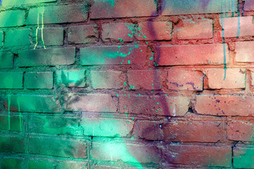 Fototapeta premium Art texture: a brick wall is painted with multi-colored spray paints. Photo of textures in the city.