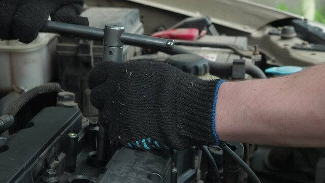 a man installs spark plugs on an old car. car repair. service