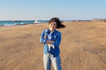 Outdoor portrait of happy woman 45 years old looking at camera with crossed arms