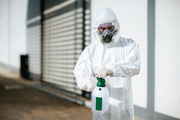 Fototapeta premium Disinfection specialist in PPE suit performing public decontamination