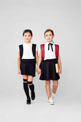 Fototapeta premium two happy little cheerful friends schoolgirls with backpacks