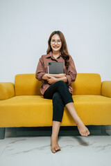 Obraz premium Portrait pretty woman sitting on sofa holding digital tablet