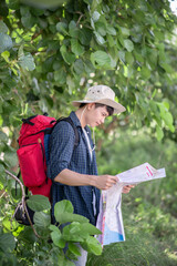 Naklejka na ściany i meble Young backpacker man looking map while working in trip
