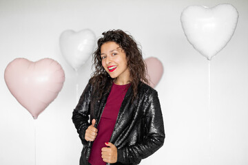 Sexy brunette girl posing with heart-shaped balloons on a white background