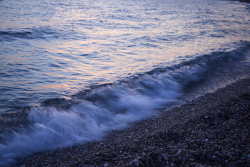 sea wave at sunset on a background of pebbles