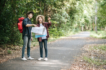 Obraz premium Young trekking couple use map while walking on forest trail