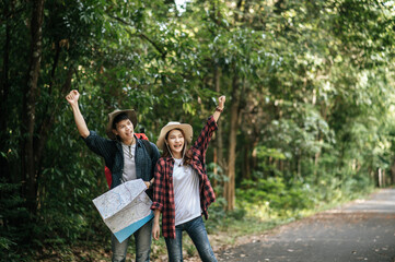 Naklejka premium Young trekking couple use map while walking on forest trail