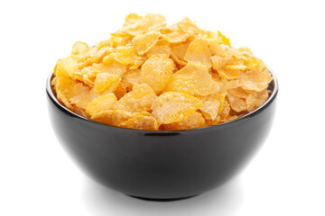 Close-Up of organic cereal corn flakes  in black ceramic bowl over white background