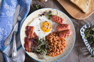 Fried eggs with bacon, sausages and beans in tomato sauce, English Breakfast