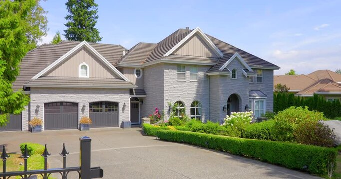 Establishing shot. Neighbourhood of luxury houses with street road, big trees and nice landscape in Vancouver, Canada. Blue sky. Day time on June 2021. Still camera view. ProRes 422 HQ.
