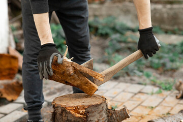 A man is sawing a tree with an ax. a strong man chopping logs with an ax. Firewood chopping process