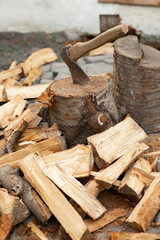 Ax and stump in the yard. Chopping firewood. Pile of wood. Wooden bars.