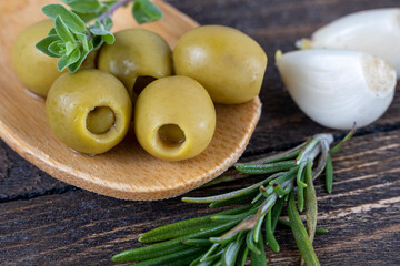 olives with spices and rosemary in a wooden spoon