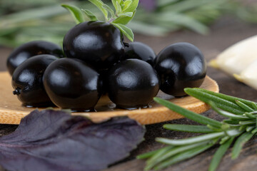 olives with spices and rosemary in a wooden spoon