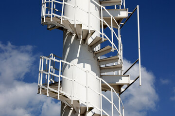 Biała wieża ze schodami na tle niebieskiego nieba.