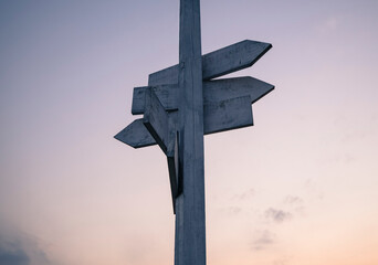 White wooden signpost with a sky during sunset in the background.