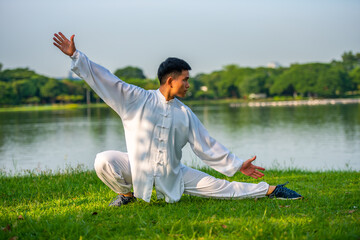 Young man doing TAI CHI exercise in the public park.