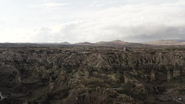 Aerial of surreal natural features of mountains on cloudy sky background. Action. Rare houses built near the picturesque rock formations. 