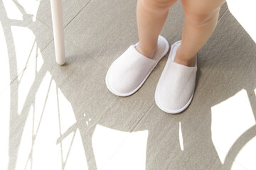 Child in blank white hotel slippers. Towelling disposable spa guest shoes. Top view.