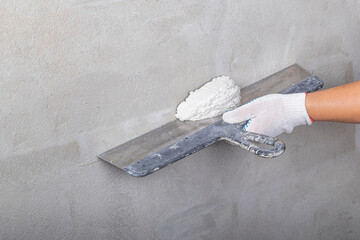 Studio lighting. the master on a metal spatula applies the solution to the wall for leveling....