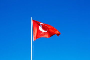 Turkish flag against clear blue sky.