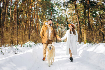 Fototapeta na wymiar Young family walks with a dog in the winter forest on vacation.
