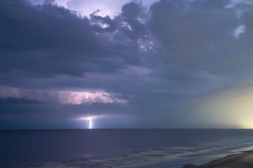 Fototapeta na wymiar Lightning lights up the night sky striking the ocean