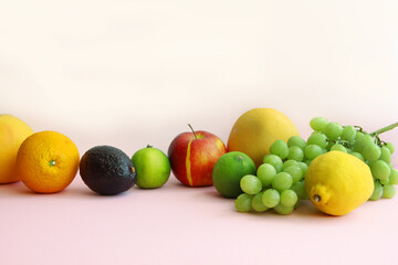 fresh fruit apple, lime, avocado, lemon, orange, grapes on a light pink background