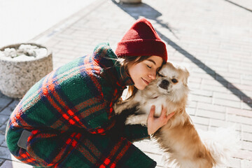 Girl walks with a dog Tibetan spaniel on a street. Selective focus, blurred background. Cold weather