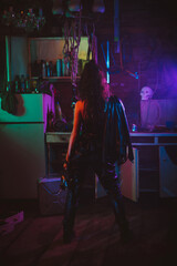 girl in a cyberpunk suit with a neon light in the garage. Steampunk cosplay in the post-apocalyptic...