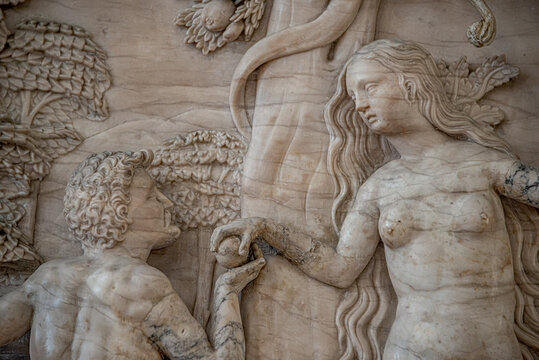 Ancient scene of beautiful Eva with an apple giving it to Adam from Bible story at Magdeburg Cathedral, Germany.