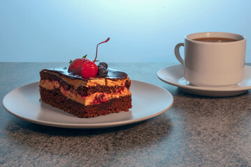 delicious fresh cake on a plate and a cup of tea on a saucer on a wooden kitchen table