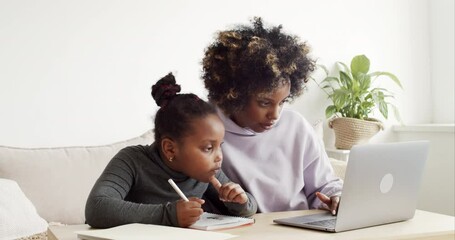 Young african mom helping her kid with homework