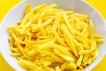 Preserved bamboo shoot in white bowl on yellow background.
