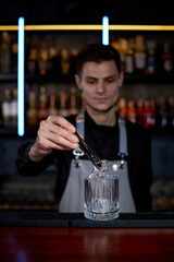 Barman puts the ice cubes into a glass