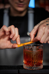 bartender makes a cocktail in a glass with orange peel