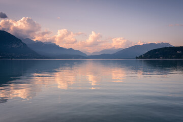 Natural landscape of Lake Annecy with colorful clouds at sunrise and Alps mountains in the background, Annecy, France