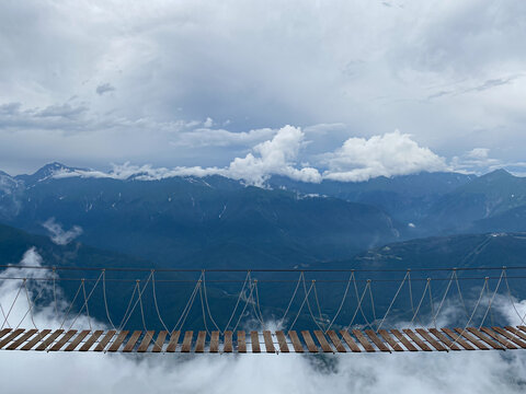 Fototapeta Rope bridge in the mountains at a height in the clouds