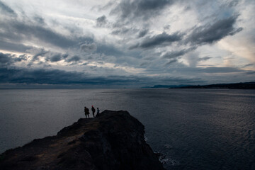 Des touristes au Cap Nègre. Des silhouettes de personnes regardant le coucher de soleil sur la mer.