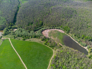Aerial sunny rural view on green pasture, forest and swamp. Greenery and wild lake drying and swamping