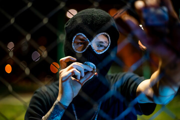 young man in balaclava looking at camera and blow smoke out. crime and violence, drugs, fashion,...