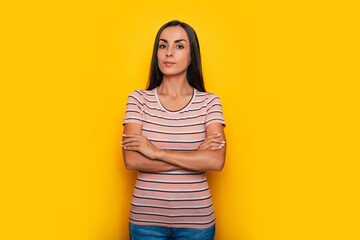 Obraz premium Happy confident beautiful young brunette woman in a t-shirt is posing and having fun isolated on the yellow background