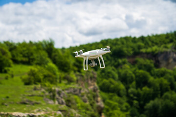 a white drone flies over the mountains and shoots a video. 