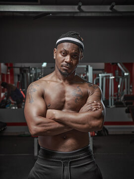 Handsome muscular athletic african american man with naked torso posing on training in gym